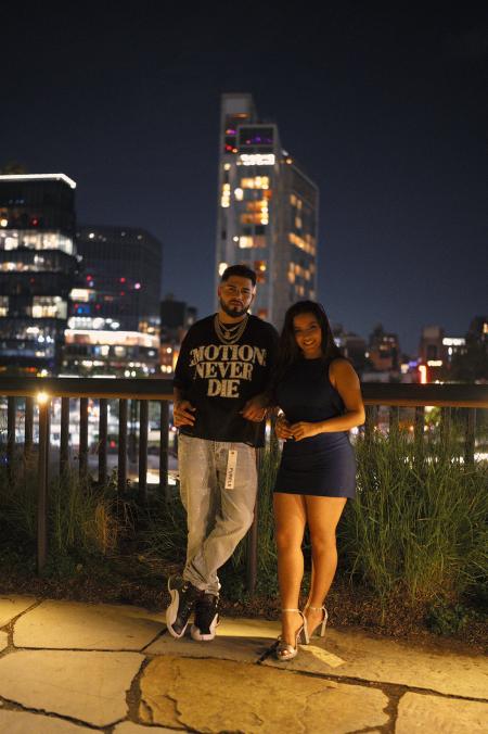 Couple standing together on a stone terrace with the city skyline lit up at night