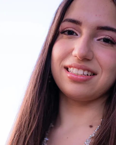 Young woman with long dark hair smiling in soft evening light