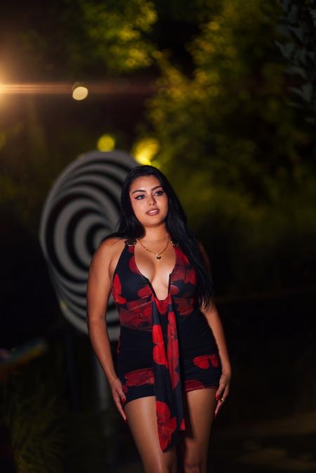 Woman in a red patterned dress standing at night in front of a large black and white spiral