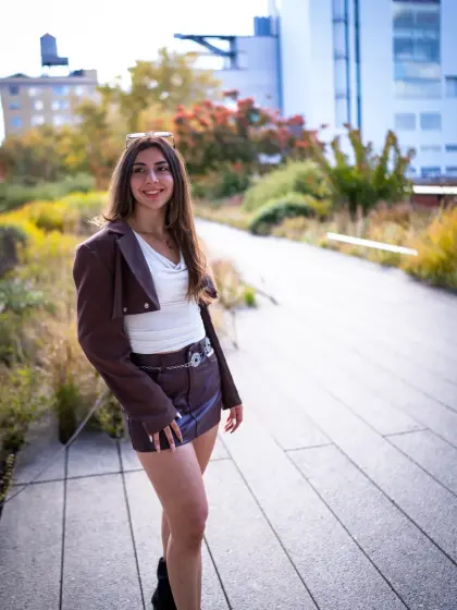 Model in a leather jacket walking an elevated city path lined with plants