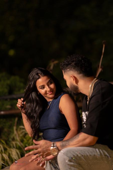 Couple seated close together on a bench at night, laughing, she in navy and he in black