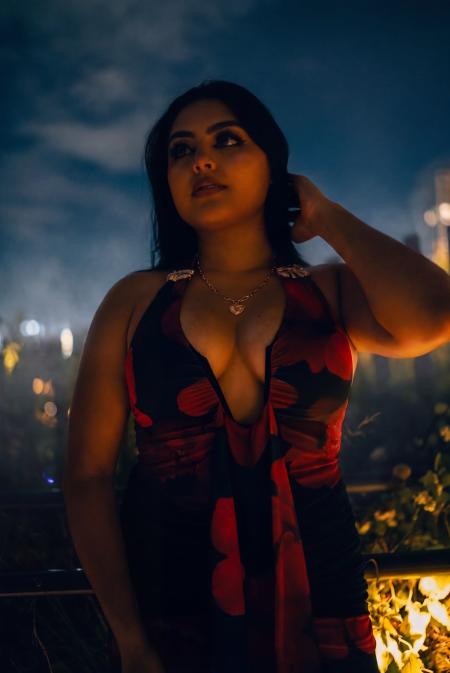 Woman in a red dress with a hand in her hair against a deep blue night sky
